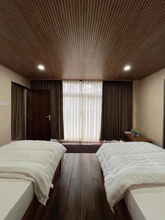 a bedroom with two beds and a large window at Zimba Cottage Retreat 2 in Kalimpong