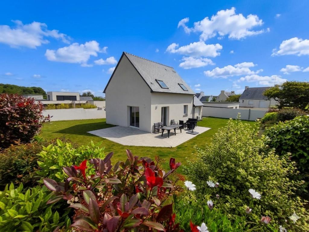 a white house with a yard with flowers at Chez Audrey et Christophe in Saint-Pol-de-Léon