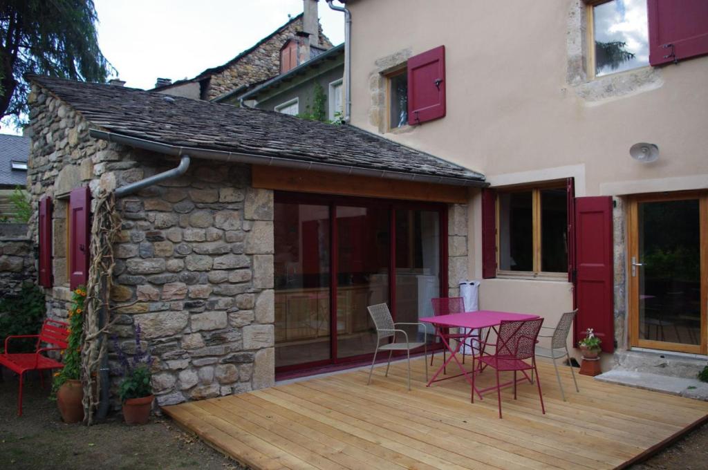 a patio with a table and chairs on a wooden deck at Chez mamiethé in Ispagnac