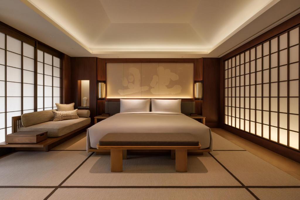 a bedroom with a bed and a couch and windows at Capella Kyoto in Kyoto