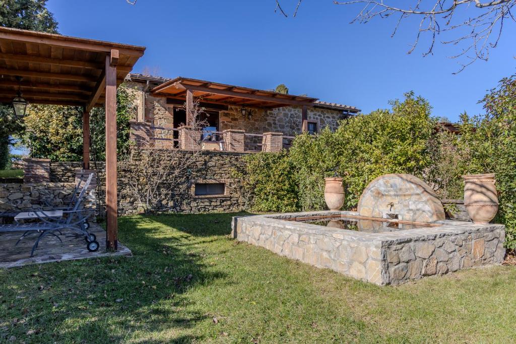a yard with a stone fountain in front of a house at Villa privata in Maremma Tuscany fontanile & wifi in Montorgiali