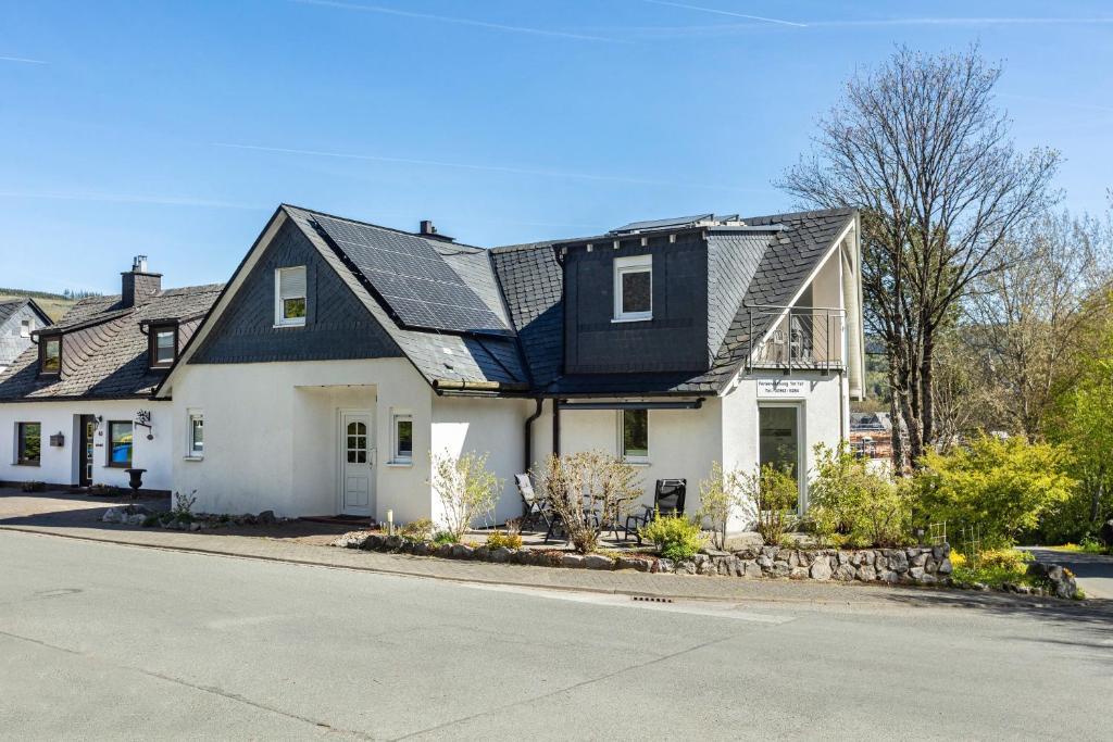 a white house with a black roof at Ferienwohnung Im Tal Olsberg in Olsberg
