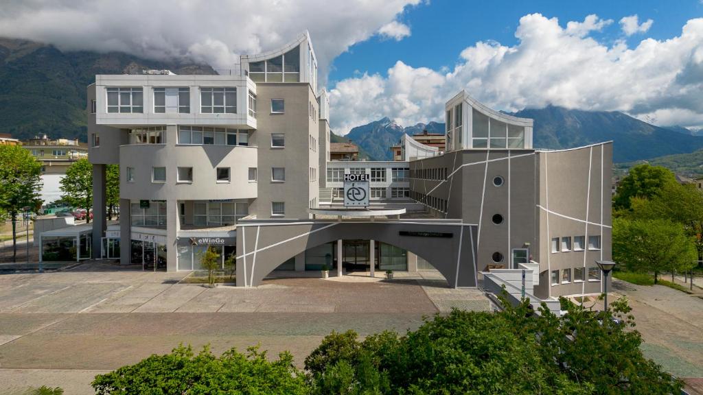 a large white building in front of a mountain at Hotel Europa Belluno in Belluno