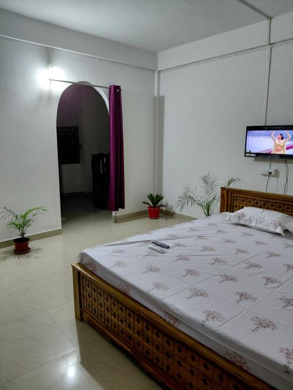 a bedroom with a large bed and a flat screen tv at Homestay in Tezpur