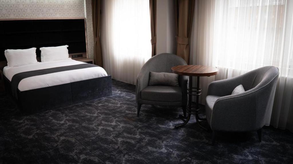 a hotel room with a bed and two chairs and a table at COMFORT HOUSE HOTEL in Pelitli