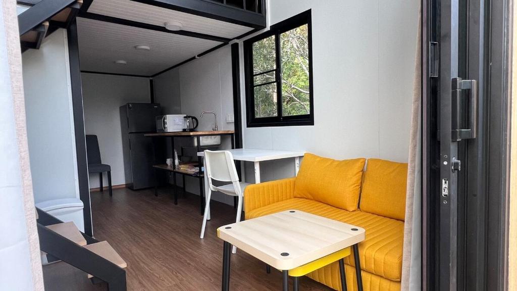 a living room with a yellow couch and a table at Duplex House in Chaloklum