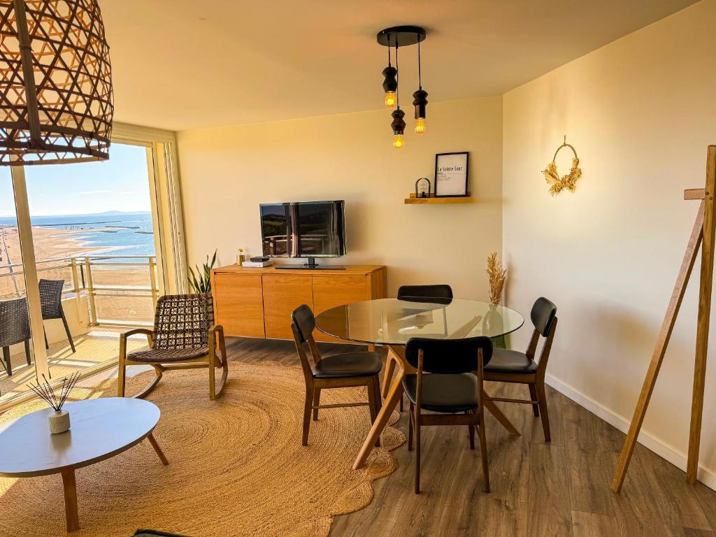 a living room with a table and chairs and a television at La Tour Myra in Valras-Plage
