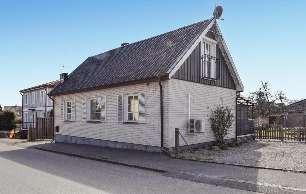 a white house with a black roof on a street at Awesome Home In Sölvesborg With Wifi in Sölvesborg