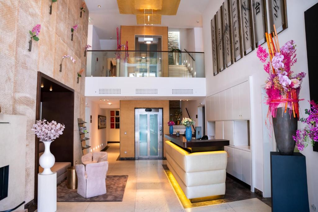 a lobby with a staircase and flowers in a building at Luxury Boutique Hotel Iris Porsche in Mondsee