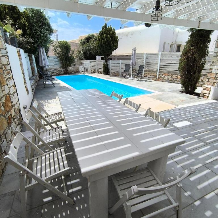 a picnic table and chairs next to a swimming pool at Theros Casa Logaras in Piso Livadi