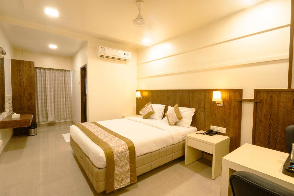 a hotel room with a bed and a desk at Hotel Sitara Residency in Navi Mumbai