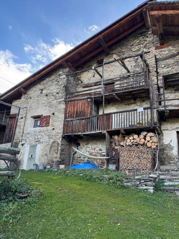 an old stone building with a balcony and logs at La Caso dal Chiot - Chalet in Elva