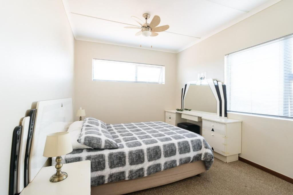 1 dormitorio con cama, tocador y espejo en Albatross Beach Guest House, en Jeffreys Bay