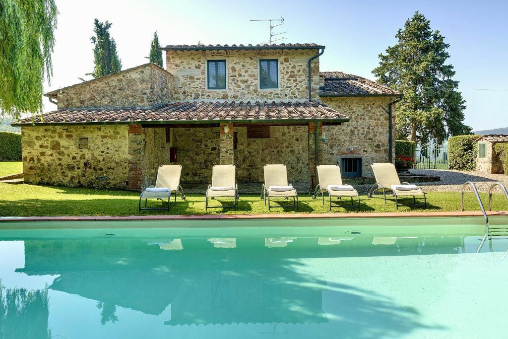a house with chairs and a pool in front of it at Riant Relais de Charme in Greve in Chianti