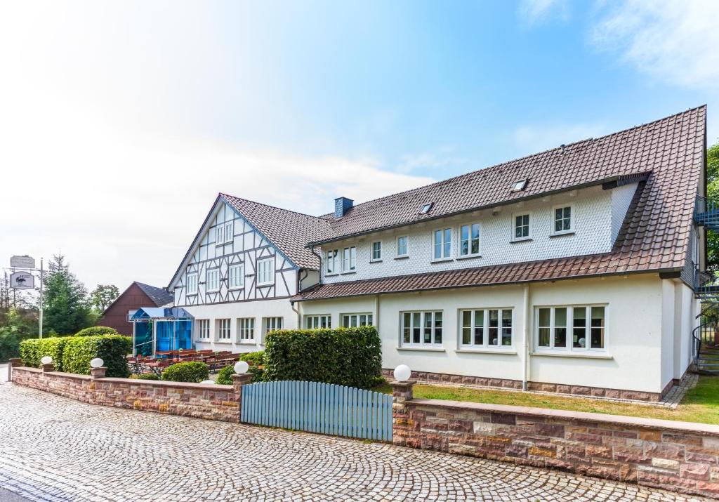 une maison blanche avec un toit marron dans l'établissement Das Landhotel am Trätzhof Fulda, à Fulde