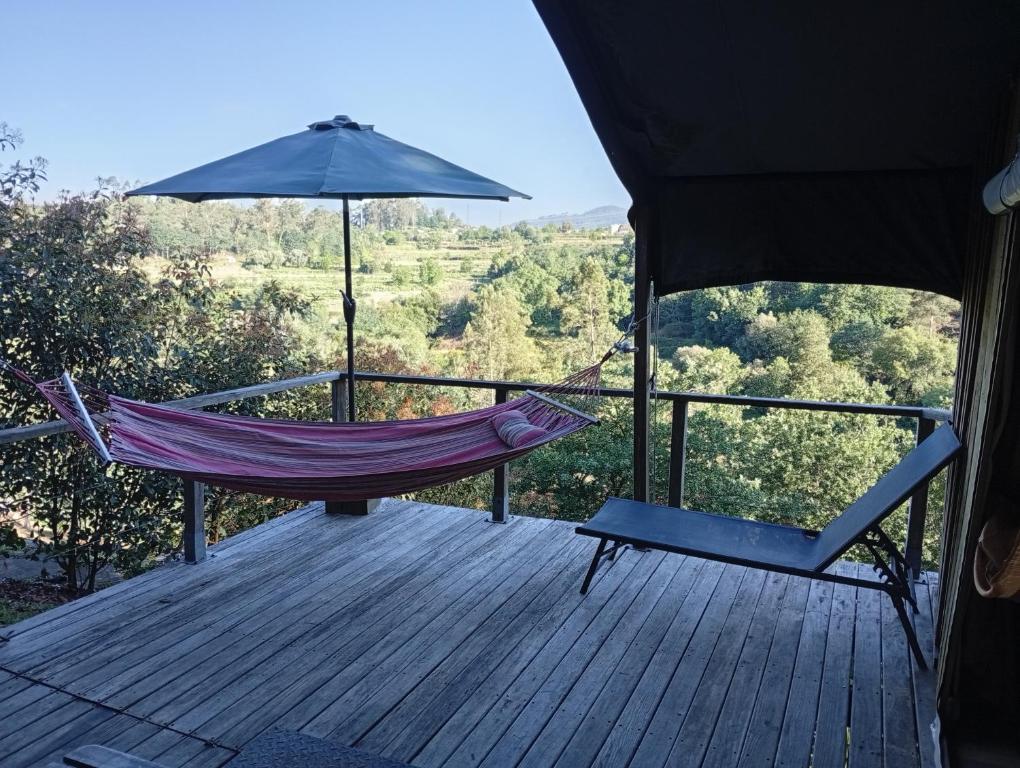 a hammock and a chair on a deck with an umbrella at African Tent in Ponte da Barca