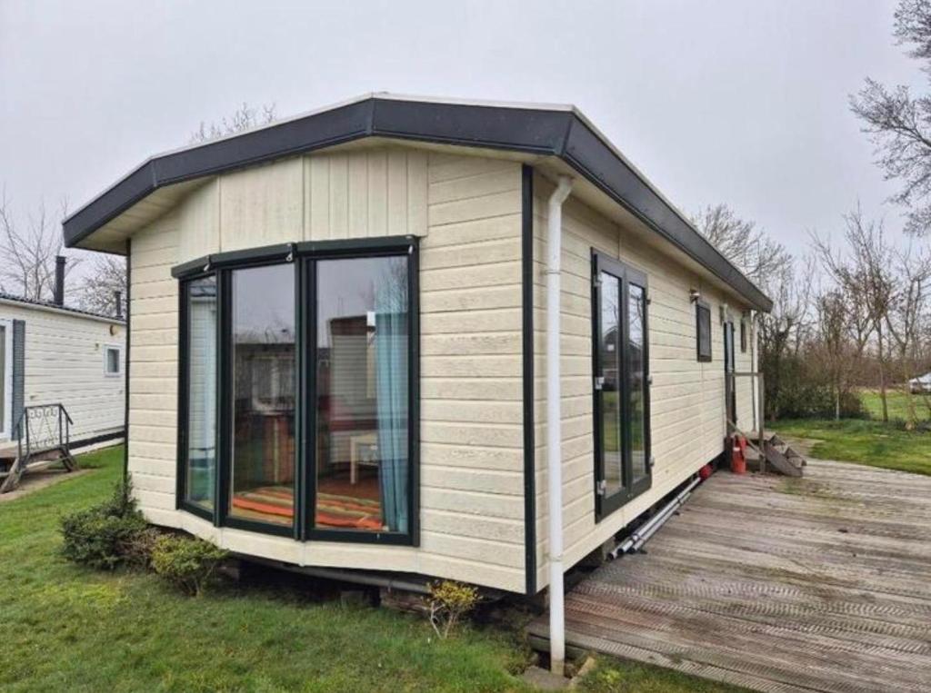 a tiny house sitting on a wooden deck at Prachtig chalet in Koudum