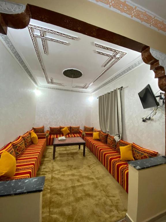 a living room with orange couches and a tv at Comfortable Luxury House in Merzouga