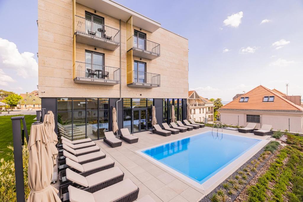 an apartment building with a swimming pool and chairs at Montello Hotel in Balatonfüred