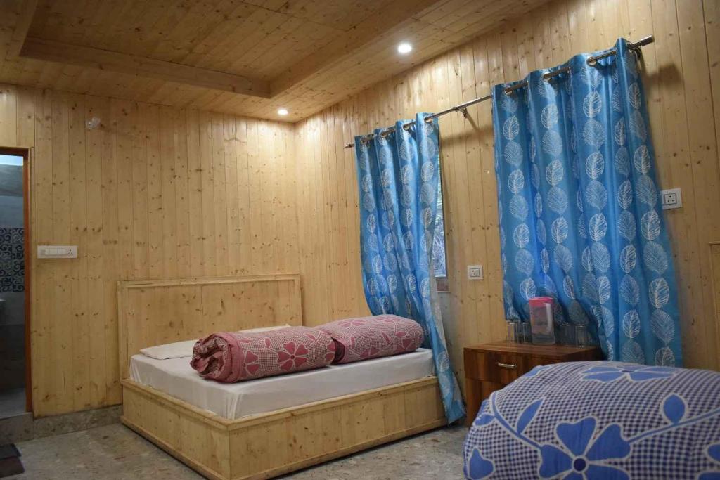 a bedroom with a bed and blue curtains at Devdaar Cottage Gangotri in Gangotri