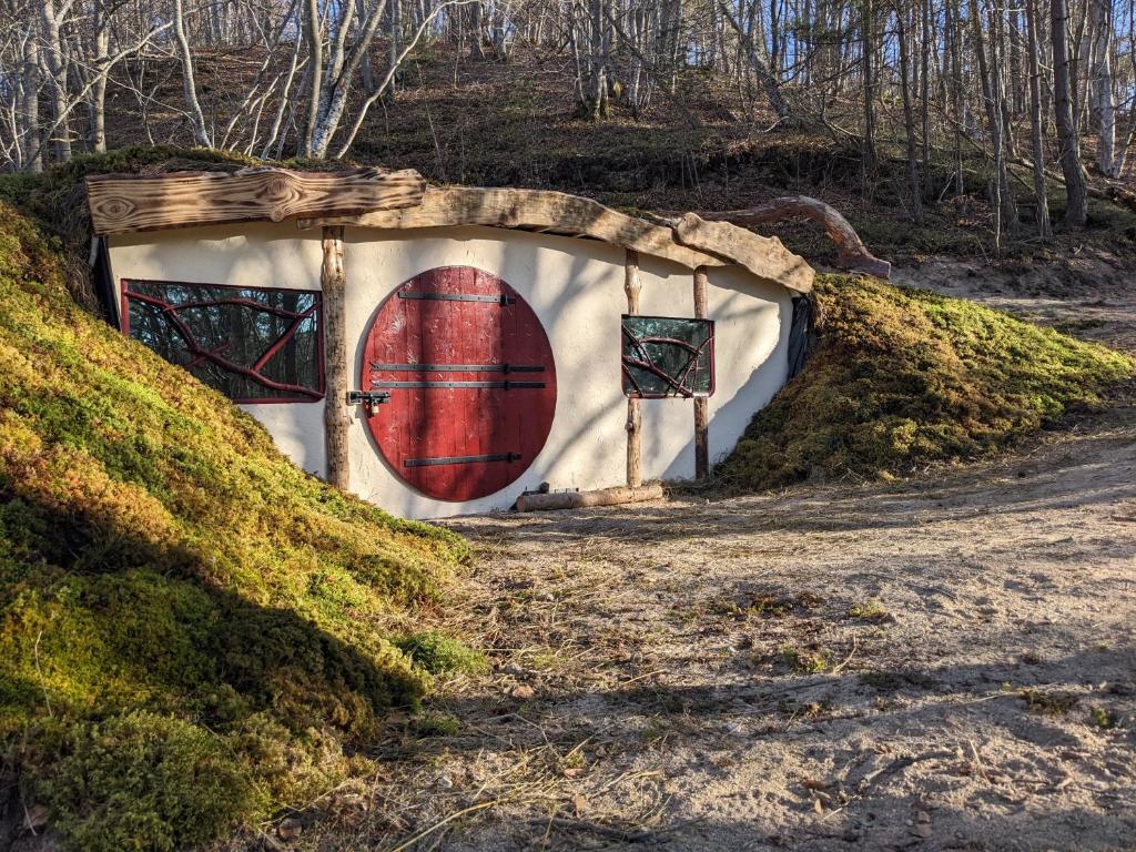 a house with a red door on a dirt road at La Maison de Hobbit in Lafarre