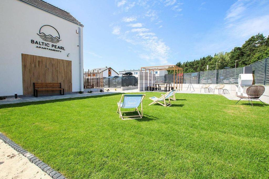two chairs sitting on the grass outside of a building at Baltic Pearl in Ustka