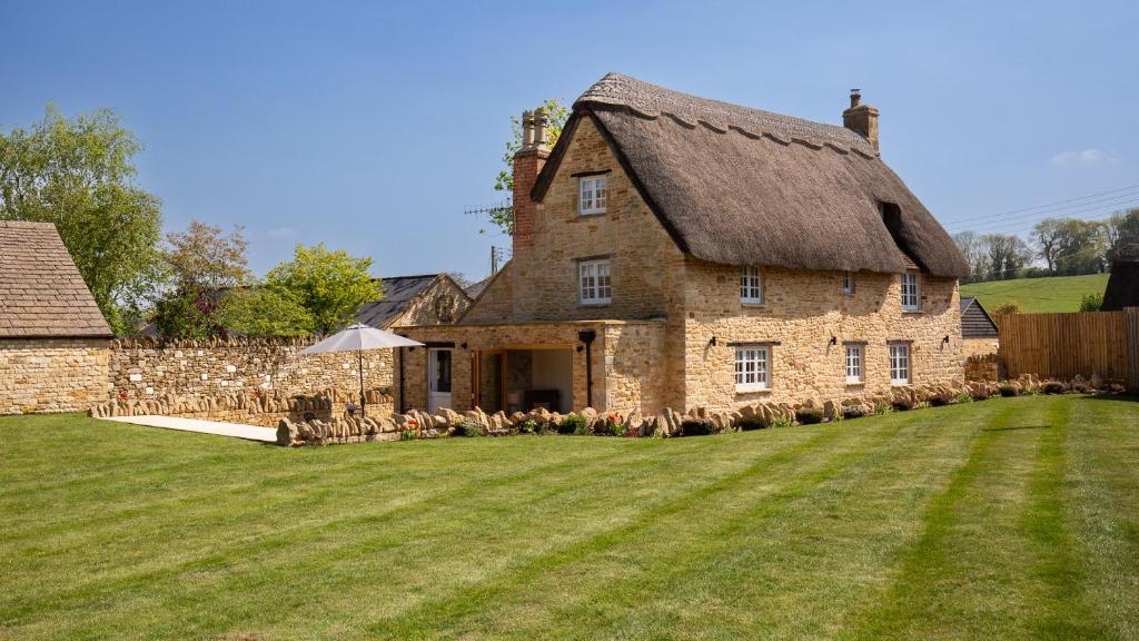 a large stone house with a thatched roof at Garden Cottage in Chipping Campden