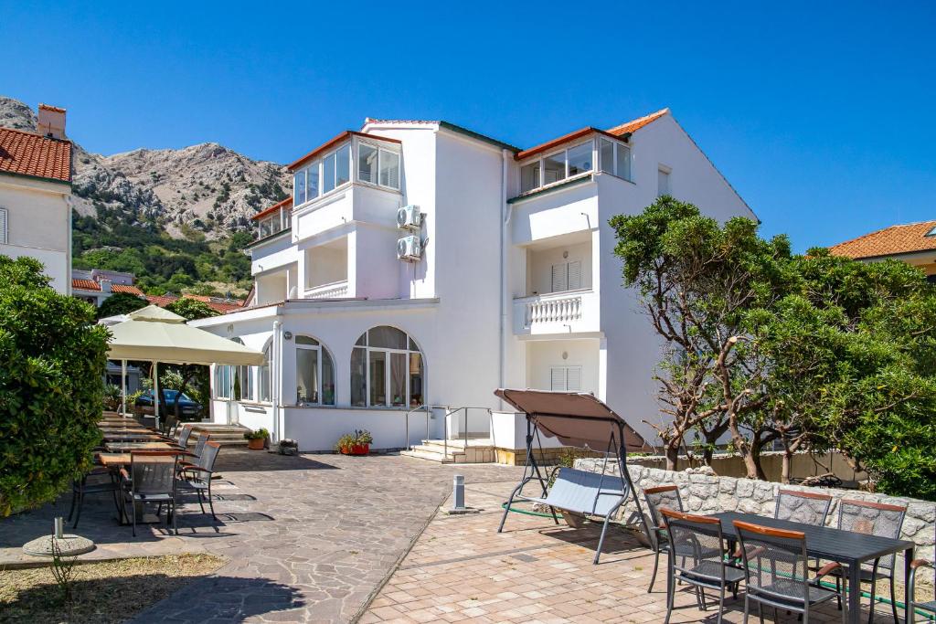 a white building with tables and chairs in front of it at Bed & Breakfast Haus Lucija in Baška