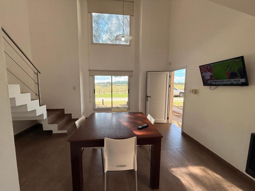 a dining room with a wooden table and white chairs at Complejo del jaguel Cabaña Antuan Aires del bosque in Santa Teresita
