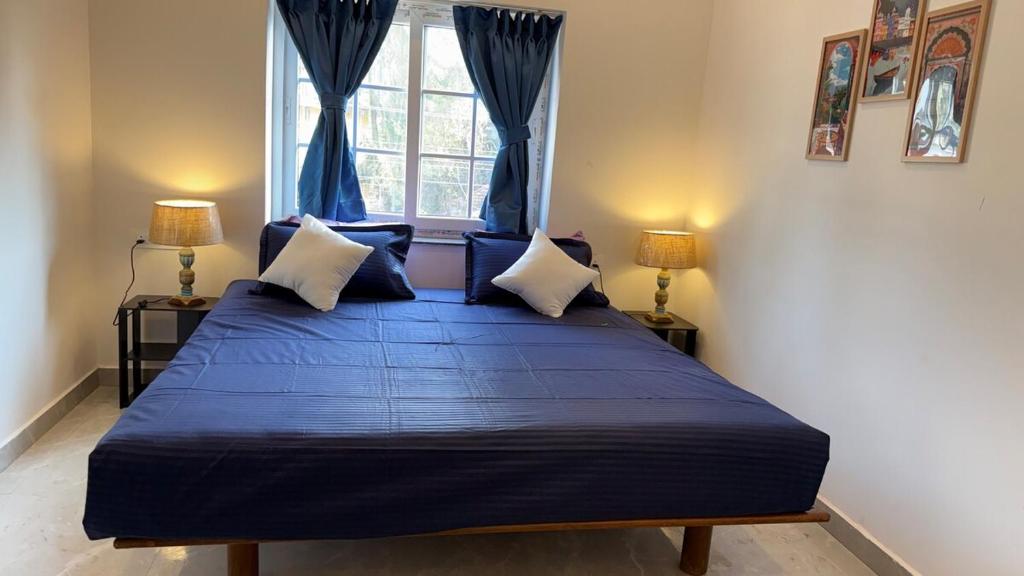 a bedroom with a bed with blue sheets and a window at Riverside By GikiJoy in Agarvado