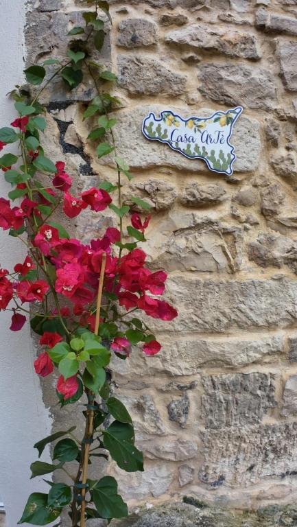 a stone wall with a sign and flowers on it at Casa ArTè in Modica