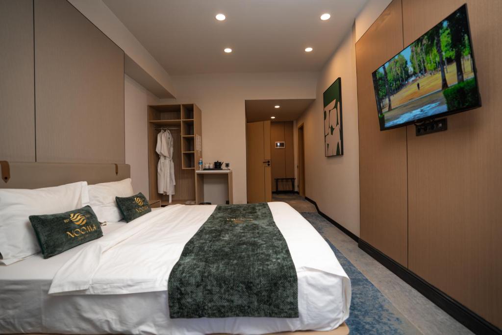 a bedroom with a large bed and a flat screen tv at NOOMA Hotel Frunze in Bishkek