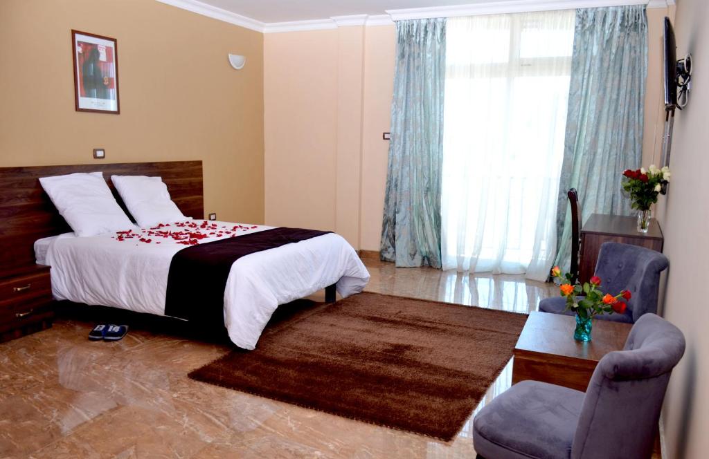 a bedroom with a bed and a chair and a window at Melodie Hotel in Addis Ababa