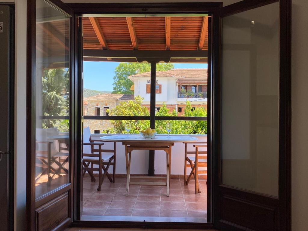 Eine Glastür führt auf eine Terrasse mit Tisch und Stühlen. in der Unterkunft Mati Kat Studios in Kala Nera