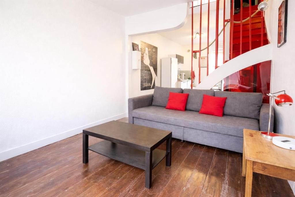 a living room with a couch with two red pillows at La Maison Créative in La Madeleine