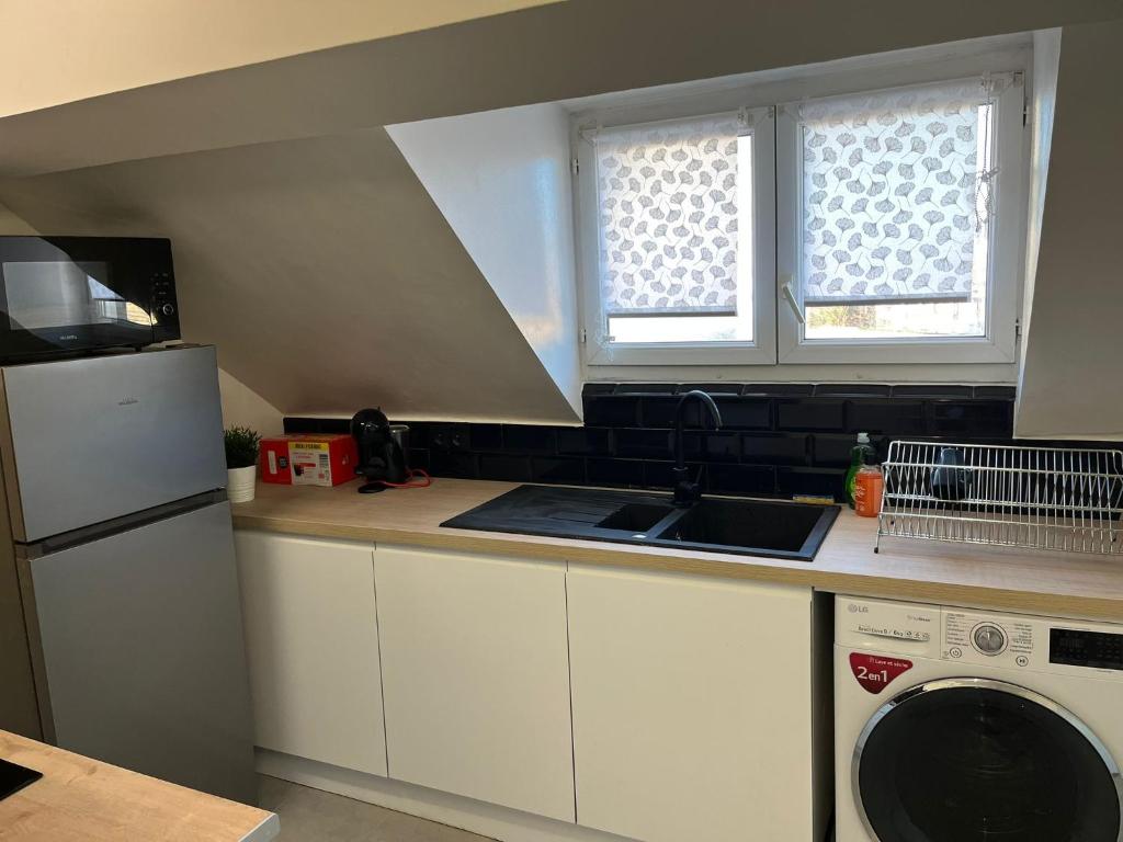 a kitchen with a sink and a washing machine at Spacieux studio in Montlhéry