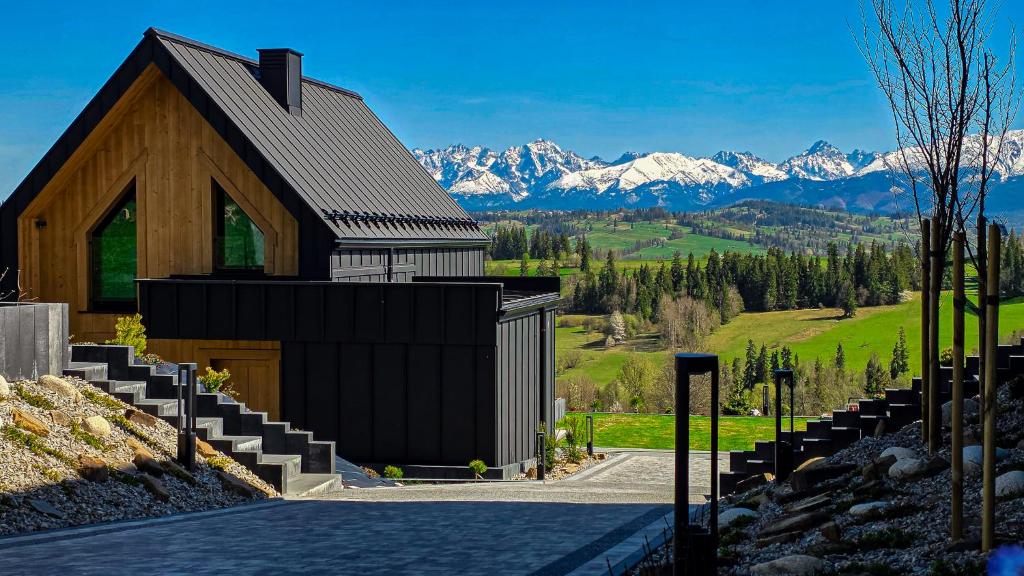 a small building with mountains in the background at Góralska Dolina II Jacuzzi & Sauna in Zakopane
