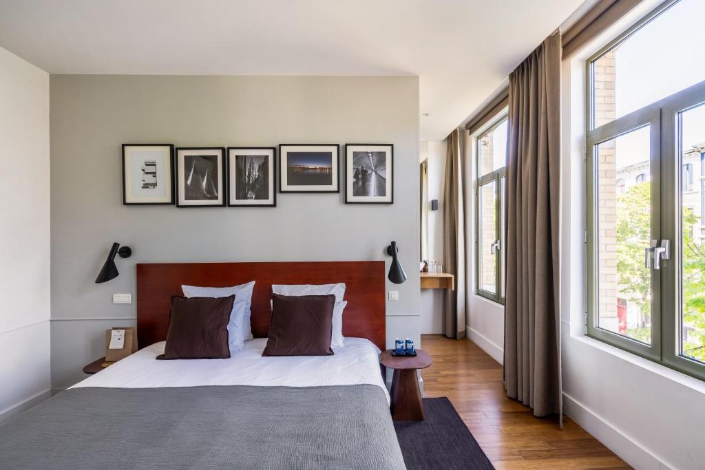 a bedroom with a large bed and some windows at A Place Antwerp - Boutique Hotel Emile in Antwerp