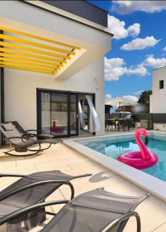 a swimming pool with a pink flamingo in a house at Jlo1 mit beheizbarem Pool in Peroj