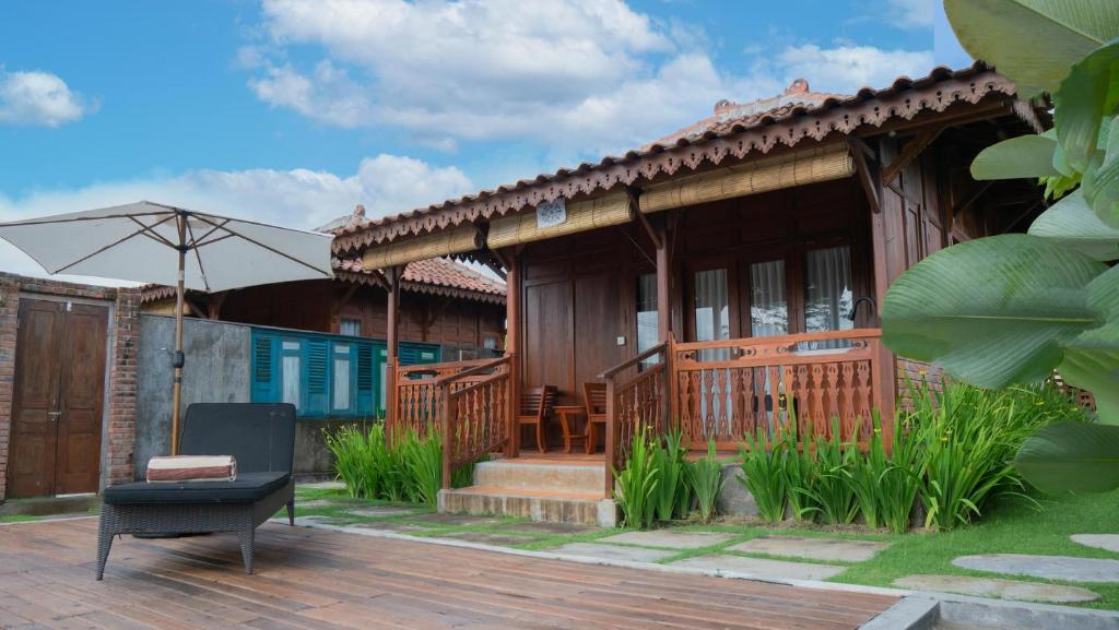 a house with an umbrella and a chair on a deck at Villa Uma Sawan By 25Hours Hospitality in Bedahulu