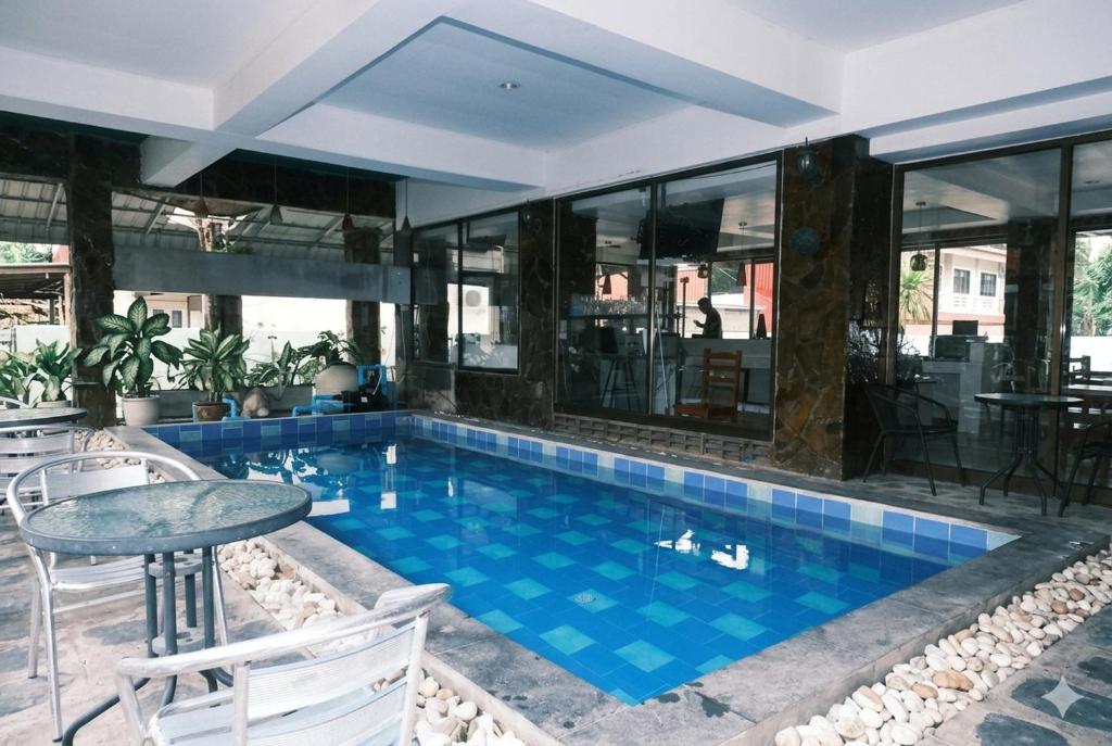 a pool in a building with a table and chairs at Collection O Luna Hotel Pattaya in Pattaya