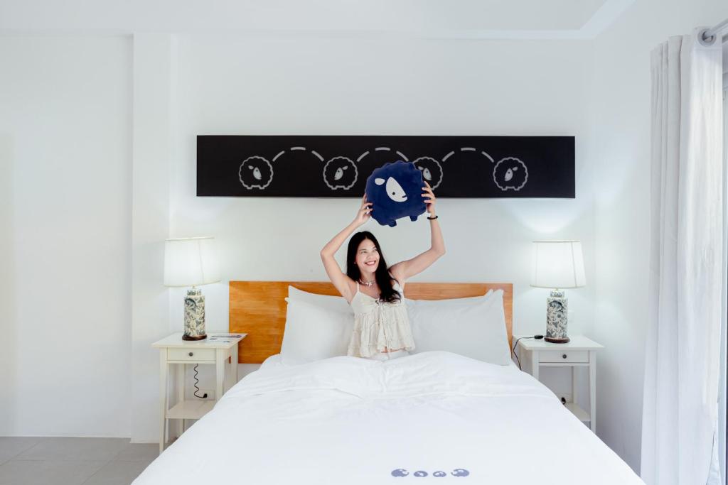 a woman is holding up a blanket on a bed at Kokotel Khao Lak Isara Casa in Khao Lak