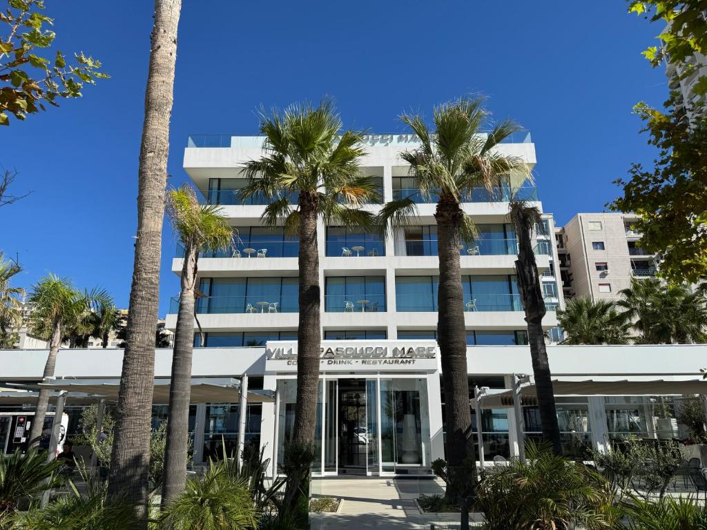 a building with palm trees in front of it at Hotel Villa Pascucci Mare in Durrës