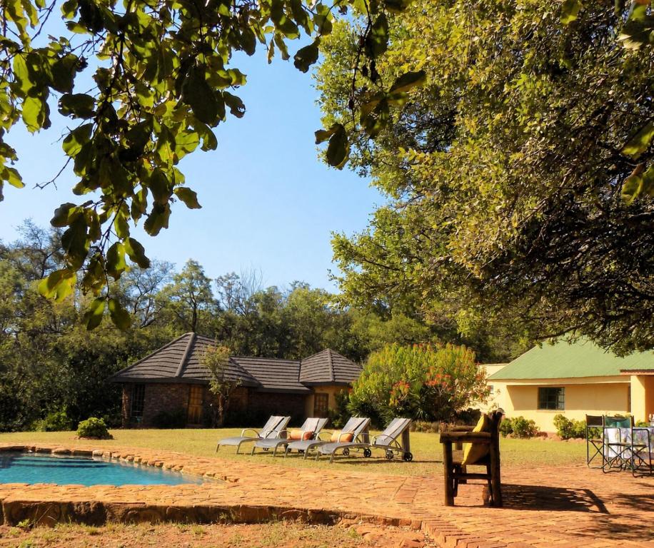 a group of chairs sitting next to a swimming pool at Palala River Cottages in Vaalwater
