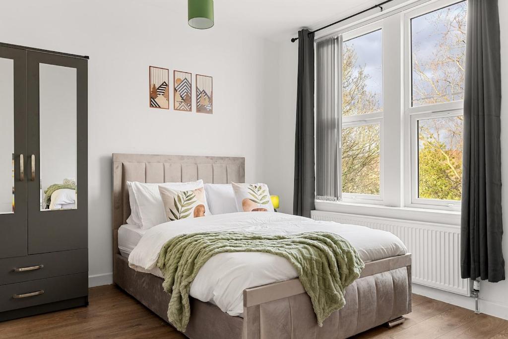 a bedroom with a large bed and two windows at Stylish & Spacious Home in the Heart of Leeds in Central Station