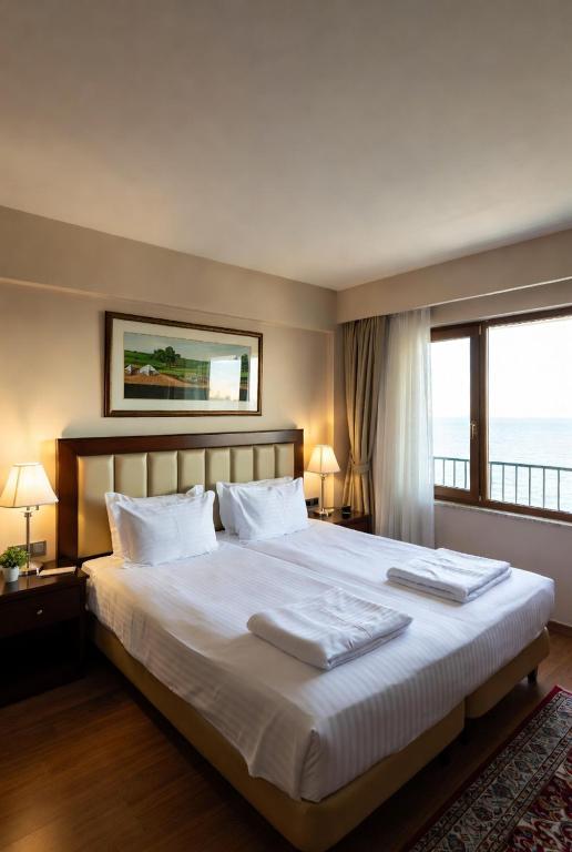 a bedroom with a large bed with a large window at Otel Ustabaş in Hopa