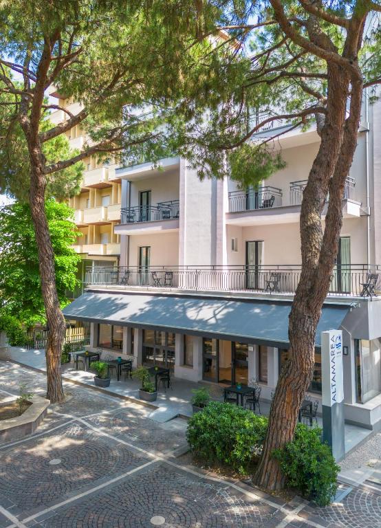 an apartment building with trees in front of it at Hotel Altamarea in Misano Adriatico