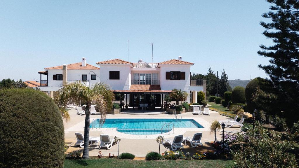 a large house with a swimming pool in front of it at Mountain view 6 bed mansion with Private Padel Court, Pool & Gym in Larnaca