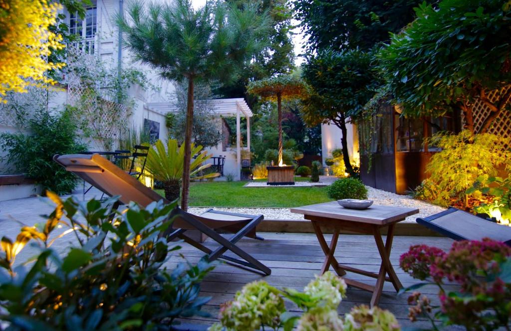 a patio with a table and a chair in a garden at Villa du Square, Luxury Guest House in Paris