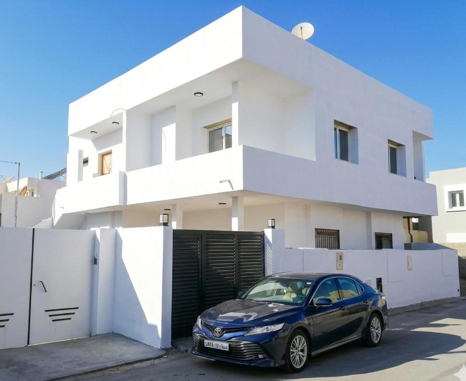 a car parked in front of a white house at Villa blanche sfax in Sfax
